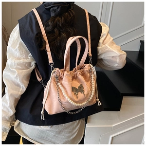 Detail of pink drawstring backpack with silver butterfly charm and pearl chain accent