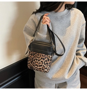 Detail of leopard print crossbody bag with black leather texture and metal zipper