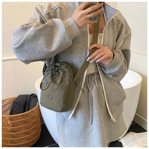Detailed view of olive green nylon drawstring crossbody bag worn with casual grey hoodie
