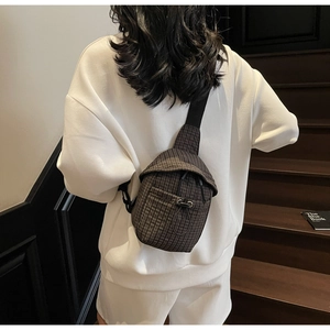 Brown checkered canvas crossbody bag shown on model climbing wooden stairs outdoors