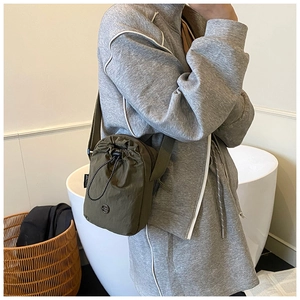 Close-up of olive green nylon drawstring crossbody bag with adjustable wide strap