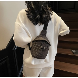 Detail of dark brown checked crossbody bag with drawstring design worn by model