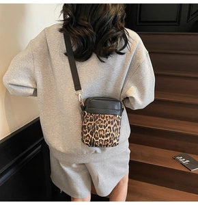 Detail of cross-body bag featuring leopard print pattern and gold metal hardware