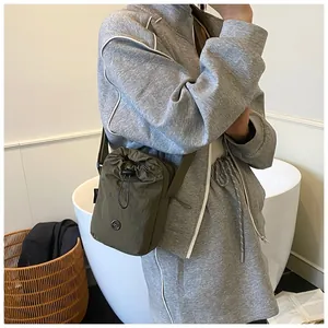 Detail of army green nylon drawstring crossbody bag with round logo and adjustable strap