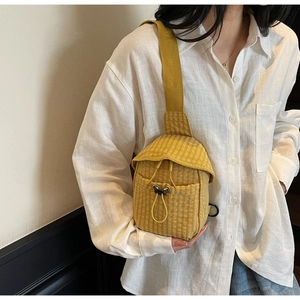 Detail of yellow checkered crossbody bag with drawstring pocket and wide strap on model