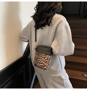 Rear view of a stylish leopard print crossbody bag worn over a casual black outfit