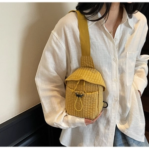 Detail of a ginger yellow checkerboard canvas crossbody bag with drawstring and flap closure