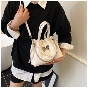 Detail of cream white pleated bucket bag with silver butterfly and pearl chain strap