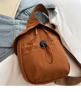 Close-up of caramel nylon crossbody bag featuring drawstring pocket and adjustable strap