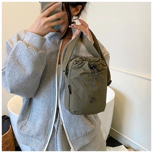 Detail of olive green nylon crossbody bag with drawstring closure and metal logo