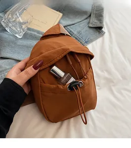 Detail of caramel brown nylon crossbody bag featuring front drawstring pocket and flap design