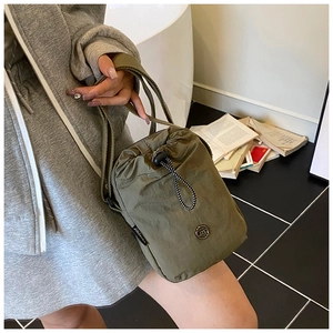 Detail of army green nylon crossbody bag showing drawstring closure and JZD metal logo