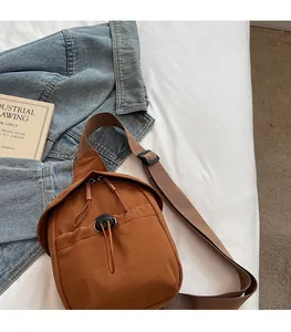 Adjustable brown nylon crossbody bag styled with a blue denim jacket and books