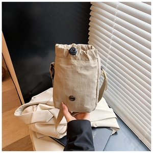 Detail of beige nylon crossbody bag with drawstring closure and wide fabric strap