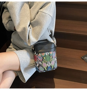 Fashionable snake pattern crossbody bag shown on a model sitting on wooden stairs