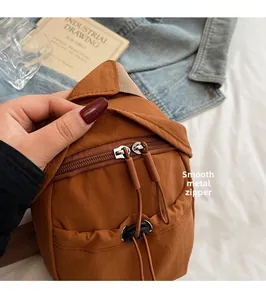 Detail of smooth metal double zippers and caramel nylon fabric on a casual crossbody bag