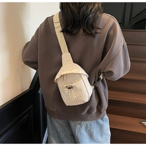 Detail of beige corduroy crossbody bag with drawstring closure and adjustable strap