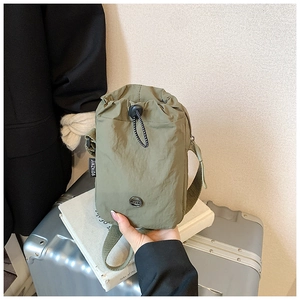 Close-up of olive green nylon crossbody bag with drawstring closure and metal JZD logo