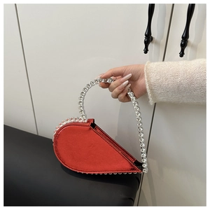 Close-up of a red asymmetrical heart-shaped handbag with sparkling rhinestones handle