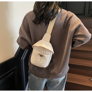 Detail of waffle-textured cream crossbody bag shown on model for size and style