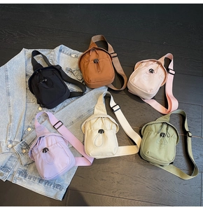 Flat lay of colorful nylon crossbody bags in six shades on dark wooden floor