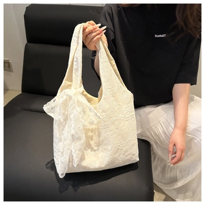 Detail of white lace tote bag featuring a large bow and intricate floral patterns