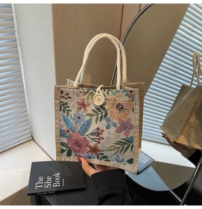 Detailaufnahme der floralen Strick-Lunchtasche mit Holzknopf und geflochtenem Griff