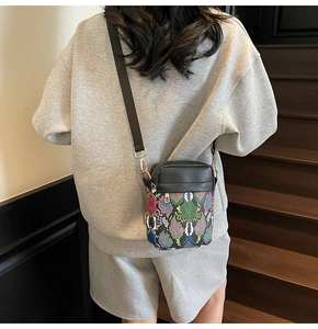 Lifestyle shot of snake pattern mini crossbody bag with gold hardware and black leather trim