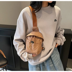Brown checkered canvas crossbody bag with adjustable wide strap shown on a model