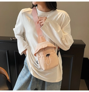 Detailed view of pink nylon crossbody bag with drawstring flap worn by female model