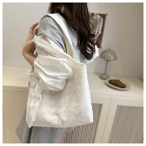 Close-up of white lace floral tote bag featuring intricate embroidery and soft texture