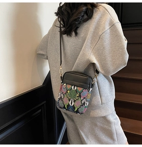 Detail of colorful snake print texture and black leather paneling on crossbody bag