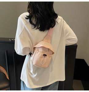 Close-up of pink canvas crossbody bag with drawstring closure and wide shoulder strap