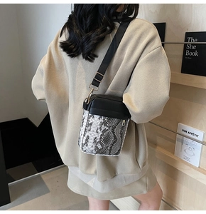 Chic patchwork crossbody bag with snake skin pattern worn by a model in a cozy library