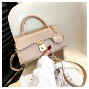 Détail du sac beige avec fermoir cadenas doré et pendentif circulaire fashion élégant