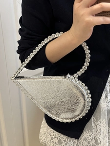 Elegant silver teardrop evening bag with sparkling rhinestone handle held by model