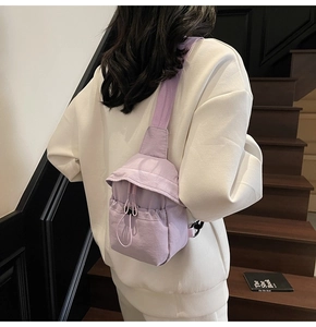 Detailed back view of a purple nylon crossbody bag with drawstring pocket on a model