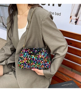 Sac à paillettes multicolores avec bandoulière dorée porté par un mannequin élégant