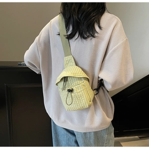 Rear view of a model wearing a light green checkered canvas crossbody bag with drawstring