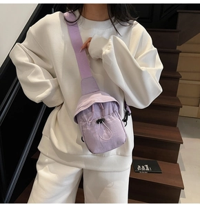 Detail of light purple nylon sling bag with drawstring closure on model near wooden stairs