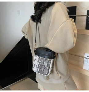 Modern cross-body bag featuring a grey snakeskin pattern and sleek black leather panels