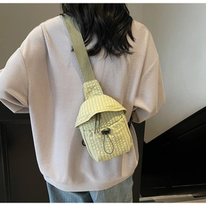 Detail of light green checkered crossbody bag with adjustable drawstring and wide strap