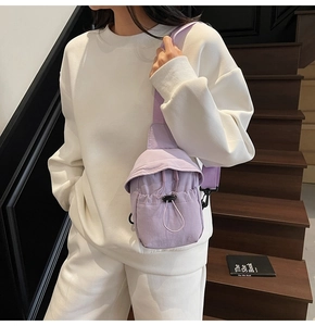 Detail of light purple nylon sling bag with drawstring closure and adjustable strap