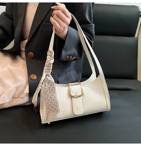 Détail d'un sac hobo blanc en similicuir crocodile avec boucle dorée et foulard en soie