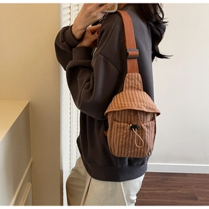 Brown striped canvas crossbody bag shown on a model with adjustable drawstring closure
