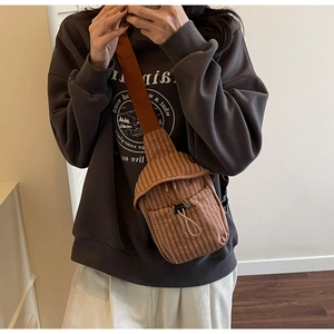 Detail of brown checkered canvas crossbody bag featuring a drawstring closure and wide strap