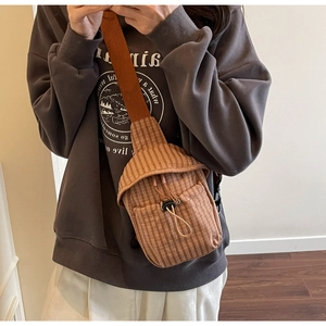 Detailed view of a brown plaid crossbody bag with drawstring closure and wide strap