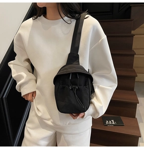 Close-up of black nylon crossbody bag featuring drawstring detail and adjustable strap