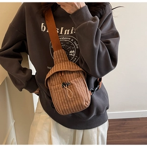 Close-up of retro brown checkered canvas crossbody bag with drawstring closure and strap