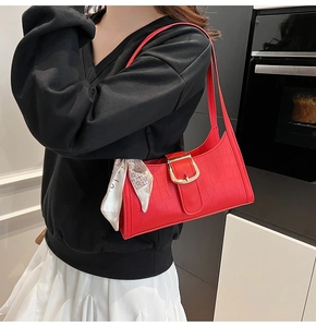 Détail du sac baguette rouge effet croco avec boucle dorée et décor de foulard en soie chic